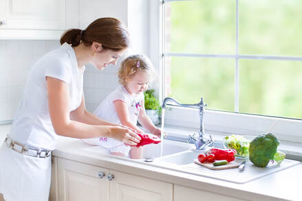 Mother and daughter washing vegetables in kitchen sink using clean, safe water that has been filtered in Orlando, FL